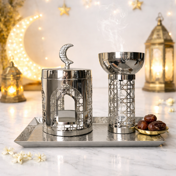 Decorative metal containers with Islamic architectural designs on a marble surface with string lights in the background.